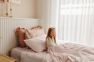 Little girl sitting up in bed with a smile on her face